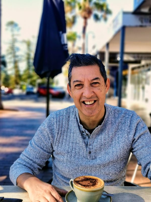 Duane, sitting at a Cairns café with a cappuccino